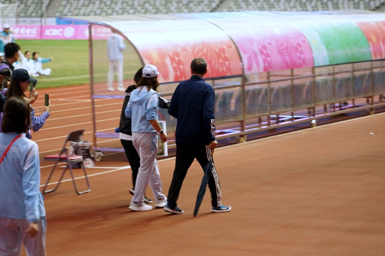 Esportes Orientais: Xu Genbao teve febre de 39 graus antes da disputa do terceiro lugar. Após o jogo, ele olhou para o campo ao sair com um guarda-chuva.